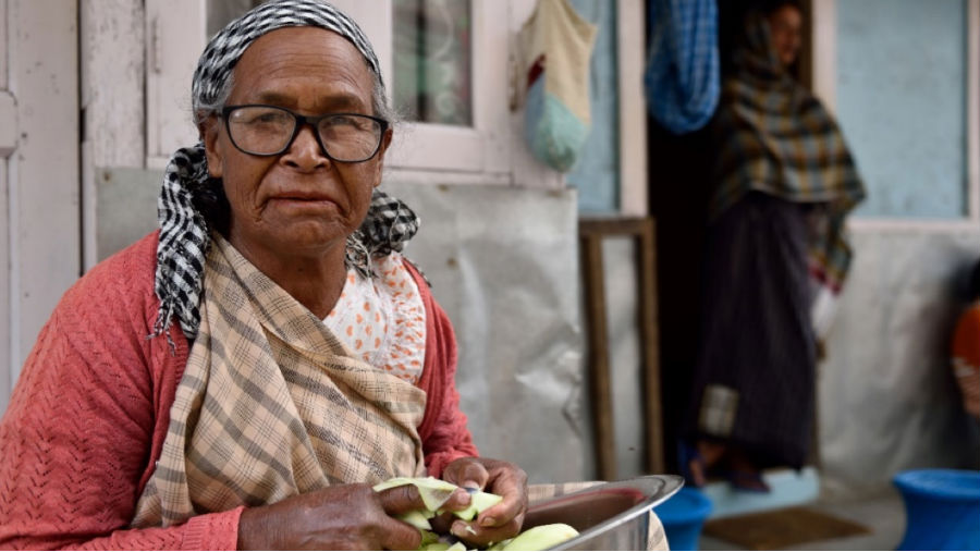 Une dame âgée avec des lunettes de soleil, des pelures et des légumes