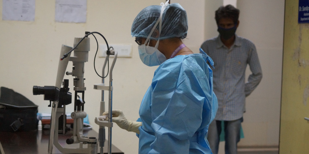 A resident cleaning the slit lamp chin rest for a patient waiting to be examined next.