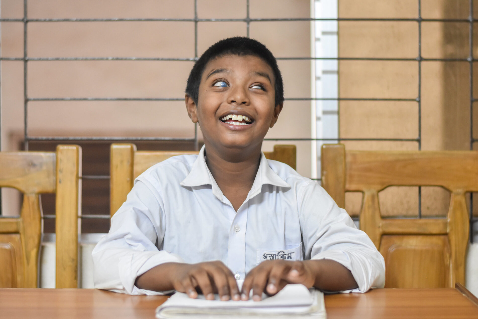 A young boy who loves to read, uses the Braille method. He is very happy to show his Braille book and talked about his future ambitions. He smiles brightly at the camera.
