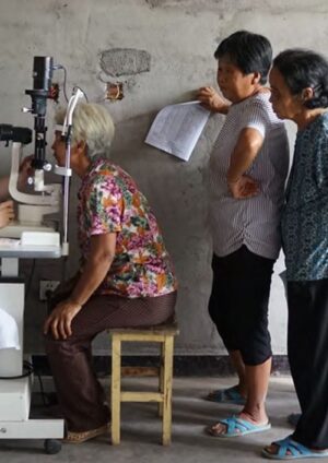 Diabetic retinopathy screening, with elderly women queueing to be examined at a slit lamp