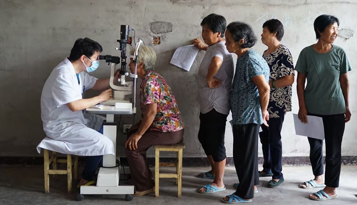 Diabetic retinopathy screening, with elderly women queueing to be examined at a slit lamp