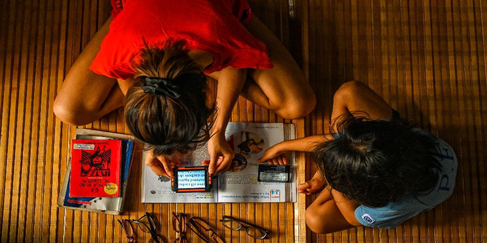 This young girl was born with a poor eyesight. She changes her glasses every year to be able to see clearly. This time her uncle gave her a digital magnifier to help her in reading books, her younger cousin looks on.