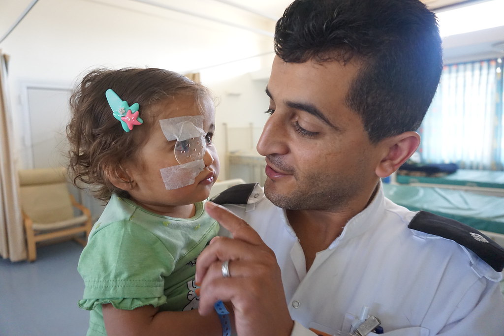 A young girl wearing an eye patch being held by a man after cataract surgery