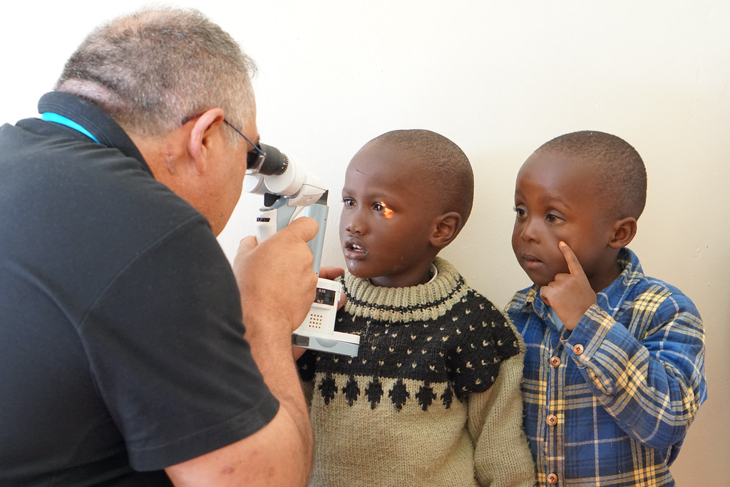 Two boys having their eye screened with portable equipment