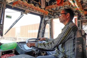 A bus driver in India wearing glasses as he drives