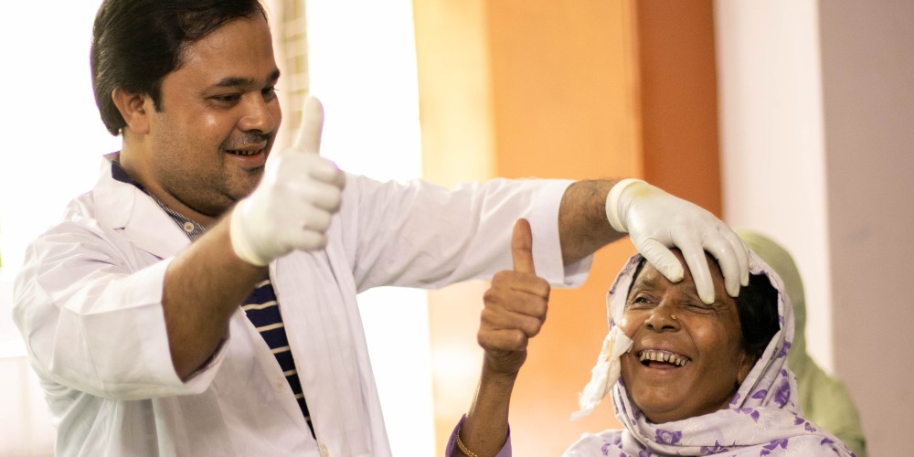 Une femme sourit alors qu'on lui enlève son bandage après une opération de la cataracte.