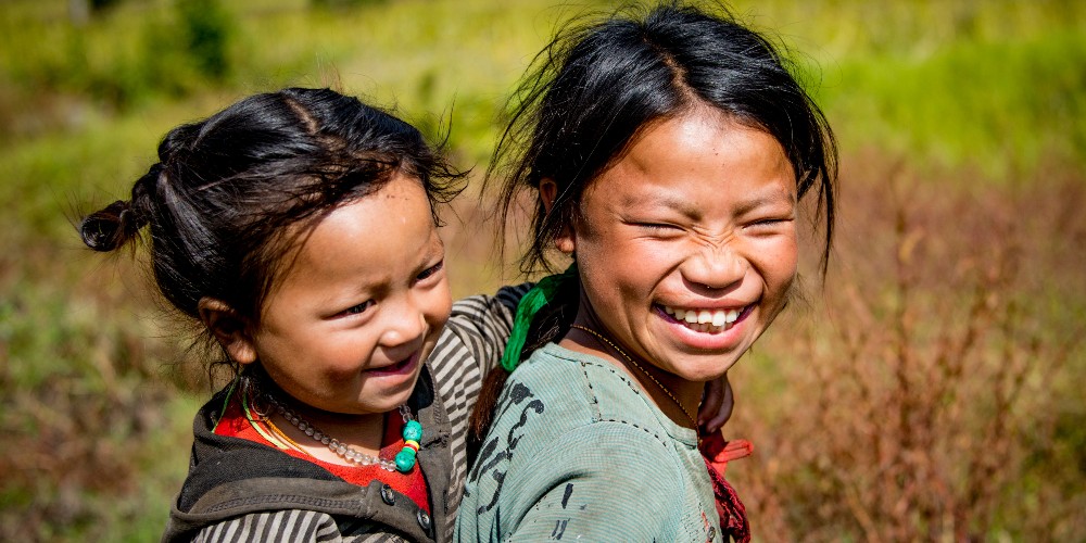 Unas hermanas nepalíes que corren y juegan juntas comparten un momento y sus sonrisas con nosotros mientras visitamos su aldea en el valle del Khumbu, en Nepal.