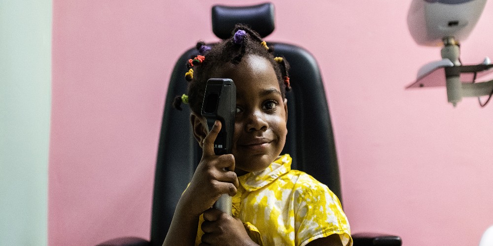 Mariya, 3 ans, joue avec un équipement médical après son examen des yeux à Yaoundé, au Cameroun. Photographié par Louis Leeson / Orbis