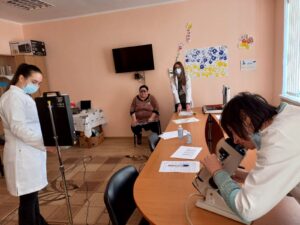 Three doctors in the frame checking vision of seated patient a woman