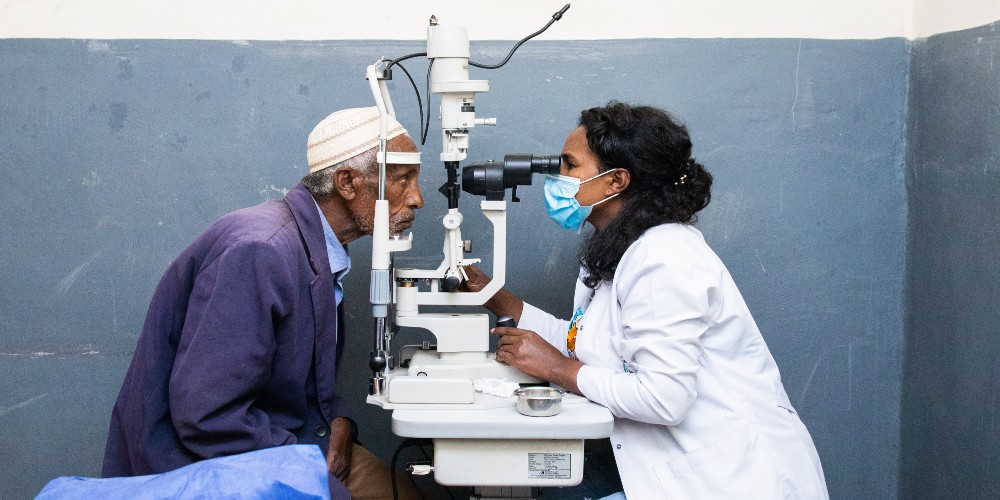 lady giving an aged man an eye exam