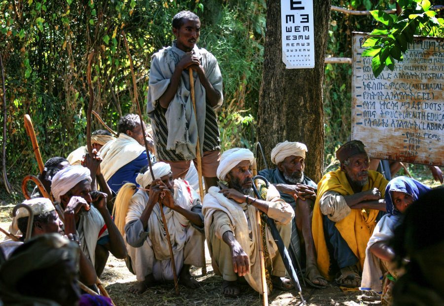 Farmers sitting under the shade of a tree a North Ethiopian rural health clinic waiting for eye tests