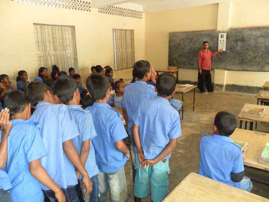 Children standing in line in a classroom waiting for an eye test