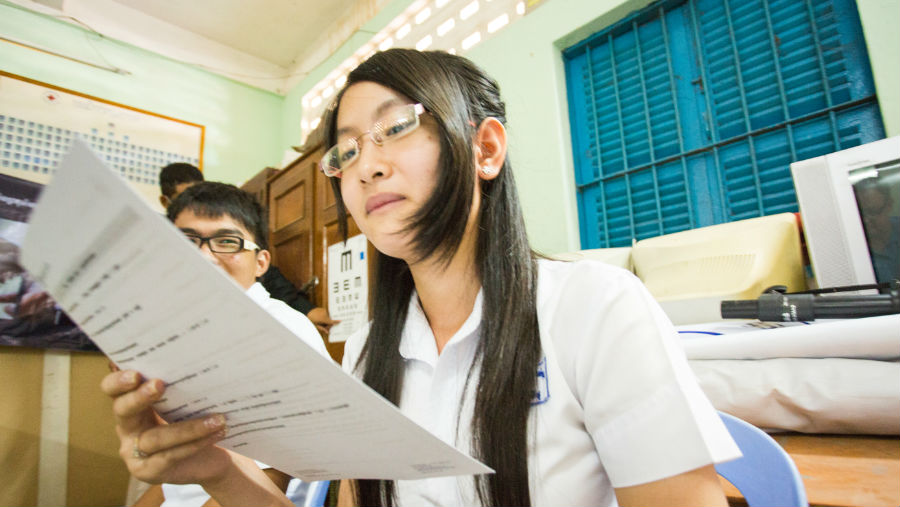 A female student with glasses reading from a paper