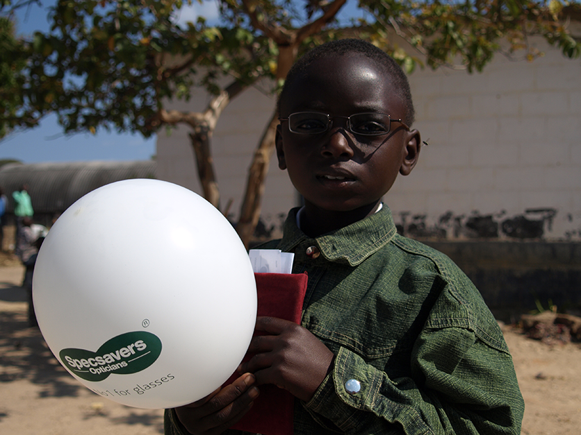 Image of a young boy with spectacles holding a specsaver balloon