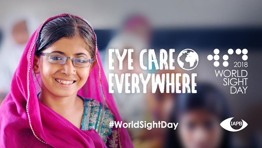 Photo of young girl with glasses smiling in class. Story: IAPB members celebrate World Sight Day 2018: a social media round-up