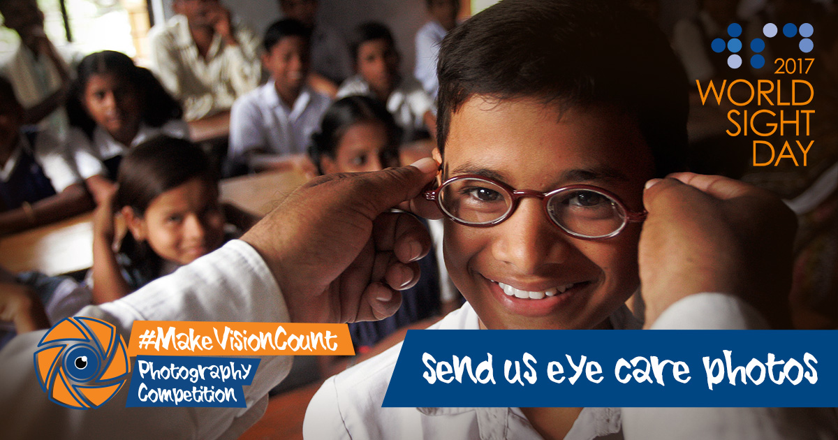 Young boy being given glasses in school while his classmates look on